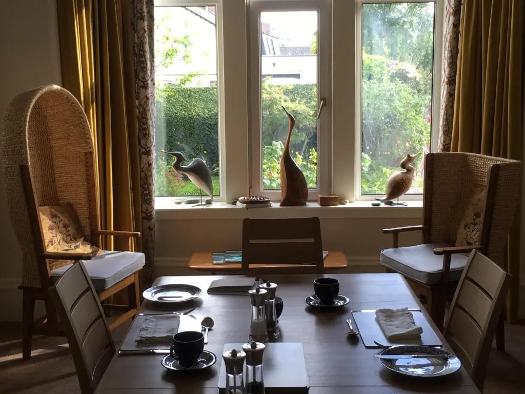 a dining room with a table and two birds on the window at Ronas House in Inverness