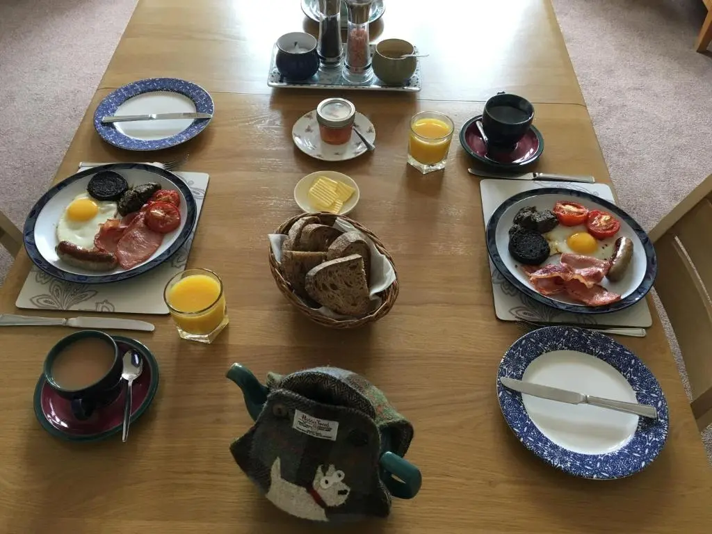 a table with plates of breakfast food on it at Ronas House in Inverness