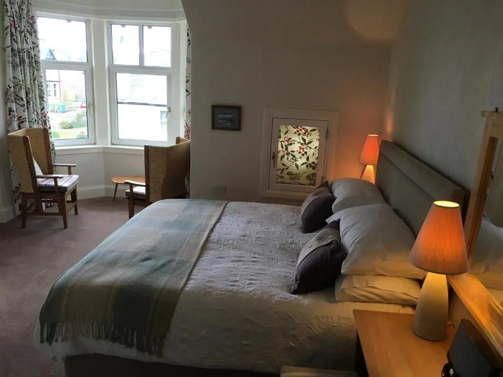 a bedroom with a bed with two lamps and a table at Ronas House in Inverness