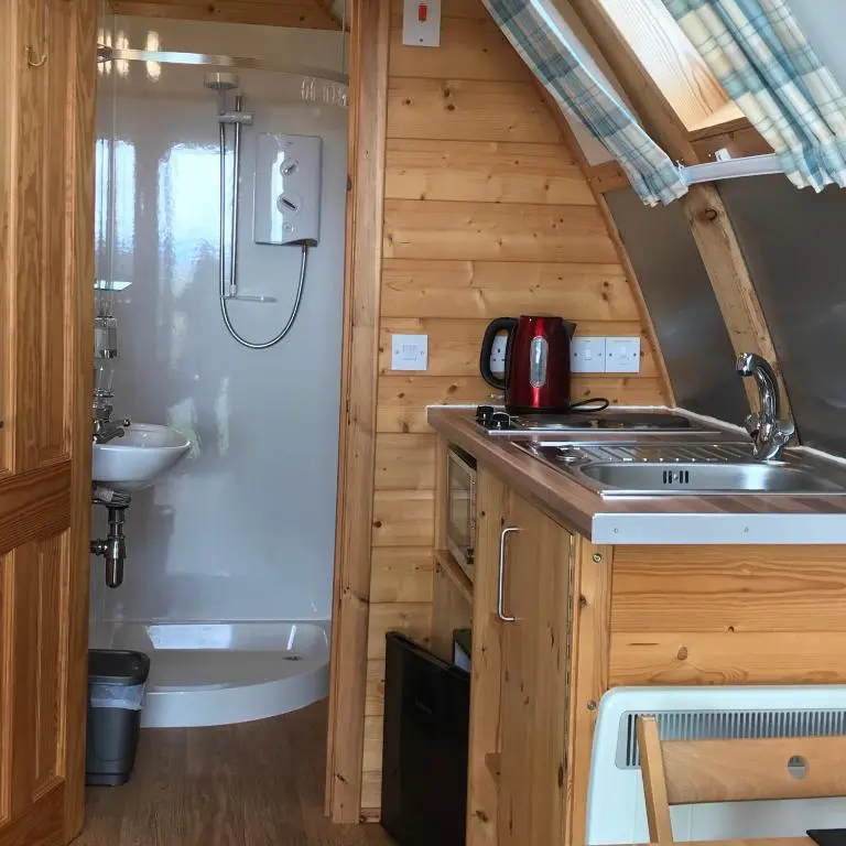 a kitchen in a tiny house with a sink and a tub at Loch Shin Glamping Pods in Lairg