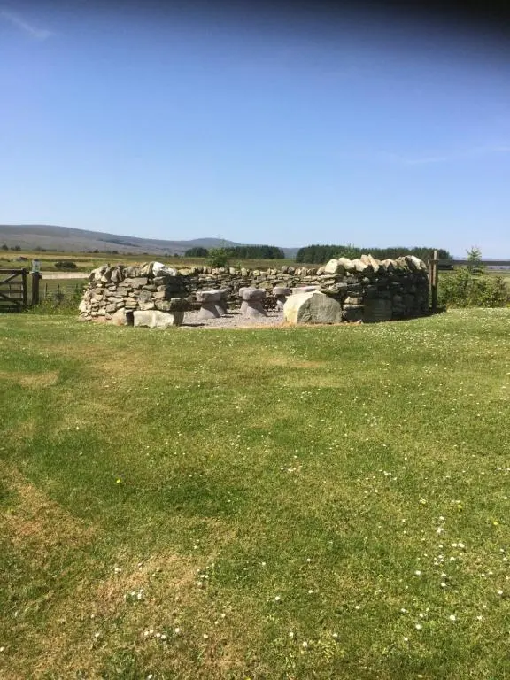 a field of grass with a pile of rocks at Loch Shin Glamping Pods in Lairg