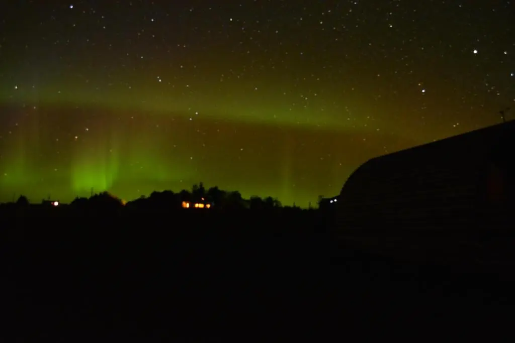 an aurora in the sky over a city at Loch Shin Glamping Pods in Lairg