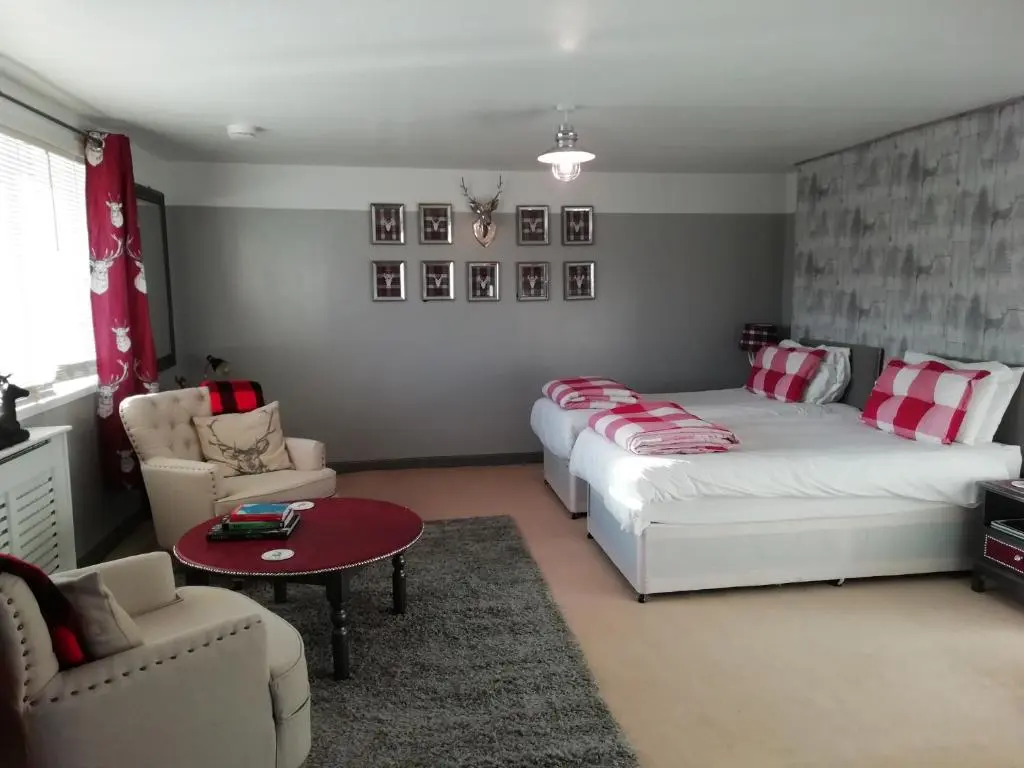 a bedroom with two beds and a couch and a table at Argyle Guest House in Tomintoul
