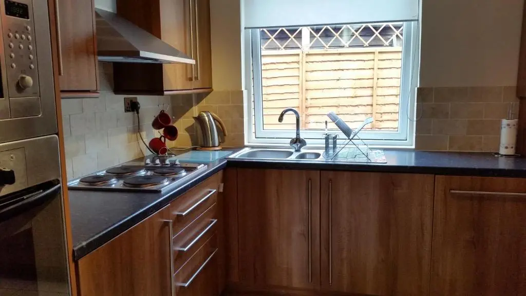 a kitchen with wooden cabinets and a sink and a window at Nairnia in Nairn