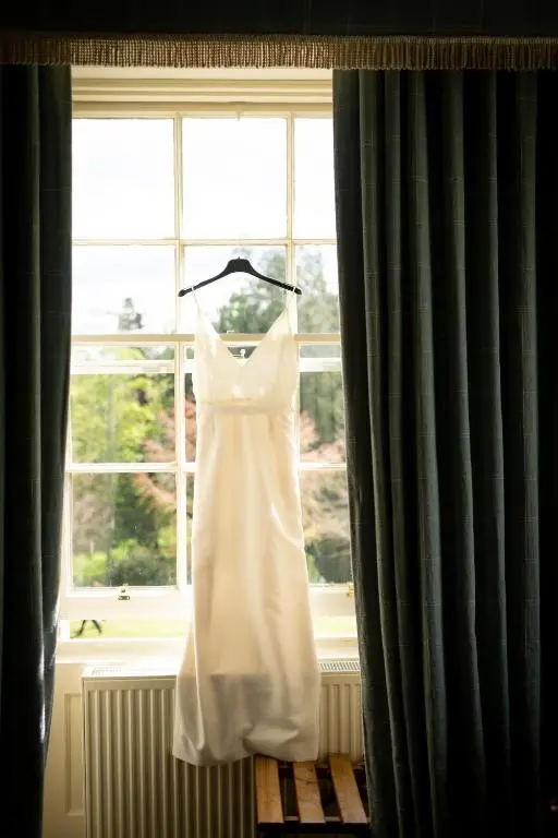 a white wedding dress hanging in a window at Dalvey House in Forres