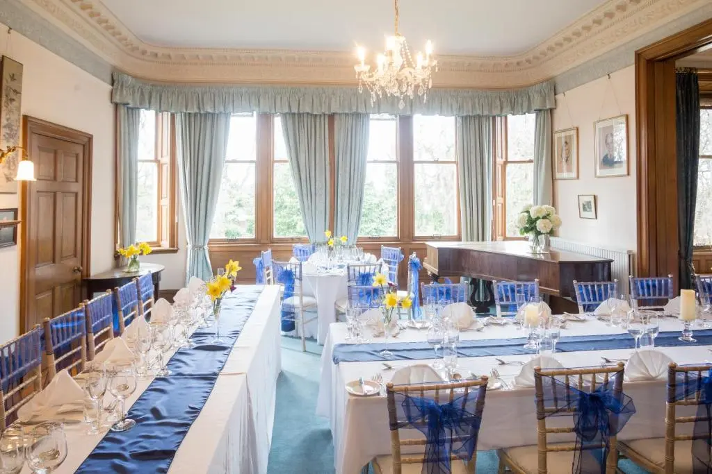 a room with long tables and blue chairs at Dalvey House in Forres