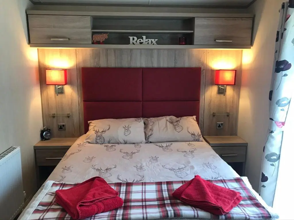 a bedroom with a bed with two red pillows on it at Riverbank Lodge in Aviemore