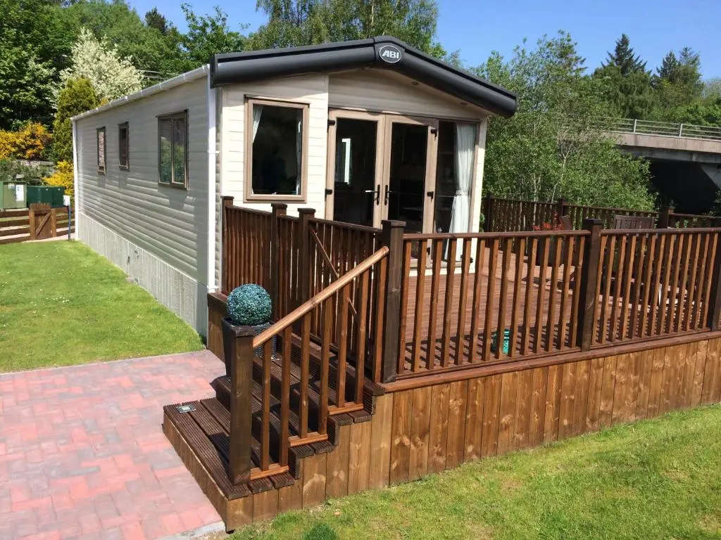 a tiny house with a wooden fence and a deck at Riverbank Lodge in Aviemore