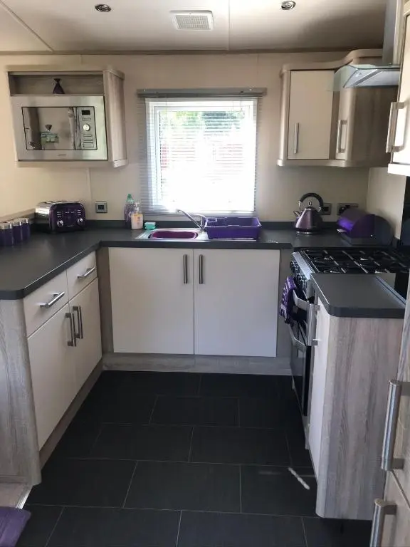 a small kitchen with white cabinets and a sink at Riverbank Lodge in Aviemore