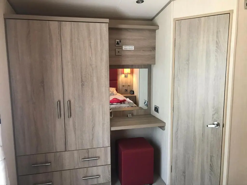 a bedroom with a cupboard and a red suitcase at Riverbank Lodge in Aviemore
