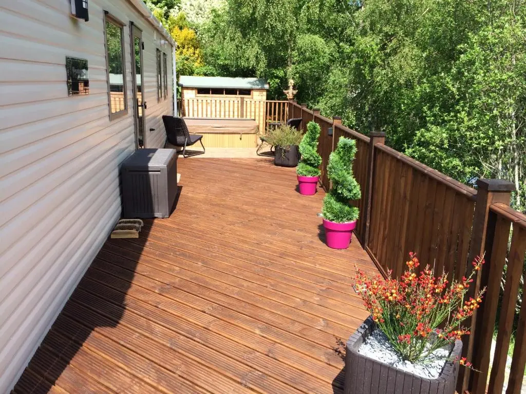 a wooden deck with potted plants on a house at Riverbank Lodge in Aviemore