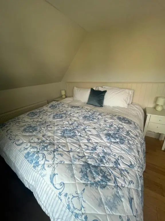 a bedroom with a bed with a blue and white comforter at Wee Corsee in Nairn