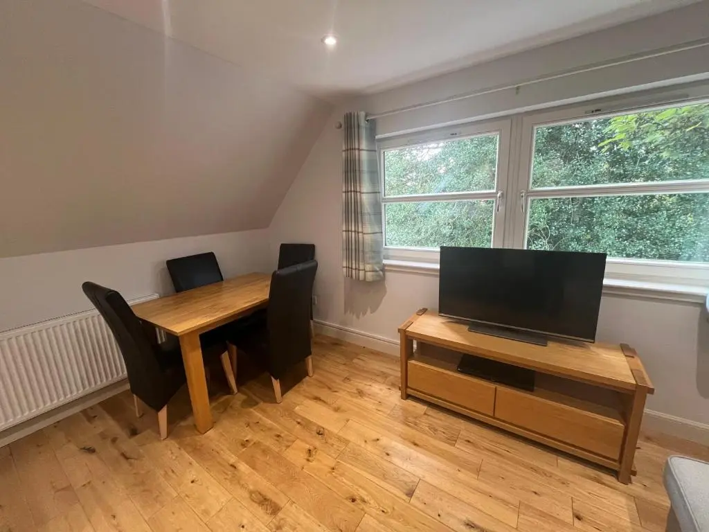 a dining room with a table with chairs and a television at Wee Corsee in Nairn