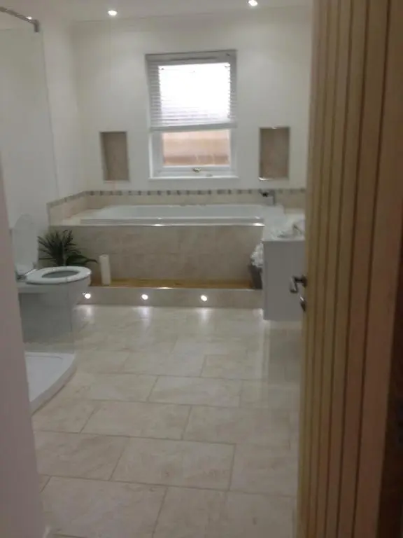 a bathroom with a tub and a toilet and a bath tub at Langley Cottage with patio, spacious rooms - part of Langley Serviced Apartments several properties in Wick in Wick