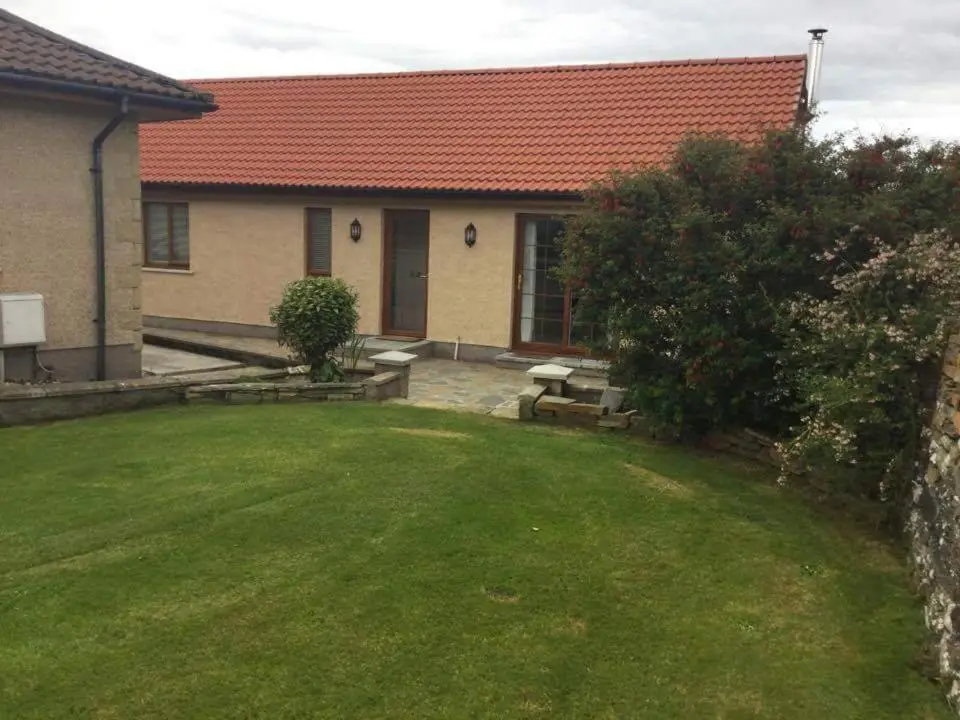 a house with a green yard with a house at Langley Cottage with patio, spacious rooms - part of Langley Serviced Apartments several properties in Wick in Wick