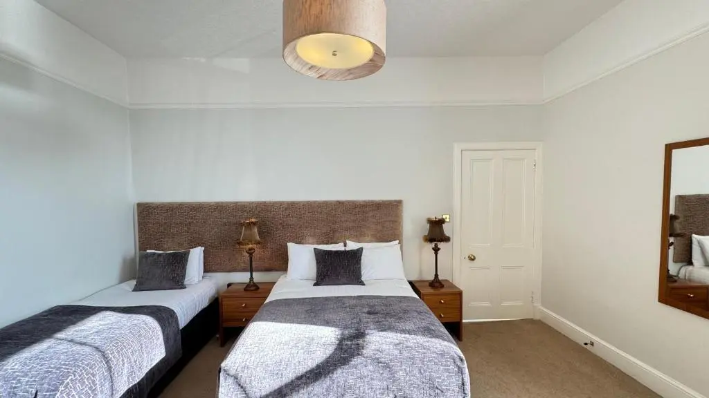 a bedroom with two beds and a mirror at Invernairne in Nairn