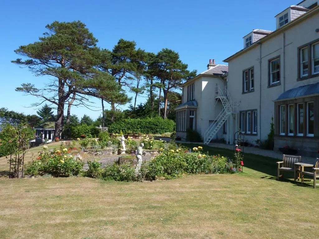 a garden with flowers in front of a building at Invernairne in Nairn