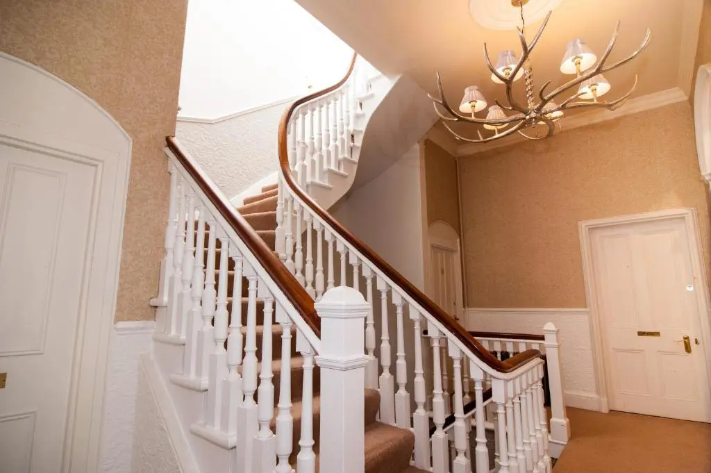 a staircase in a home with a chandelier at Invernairne in Nairn