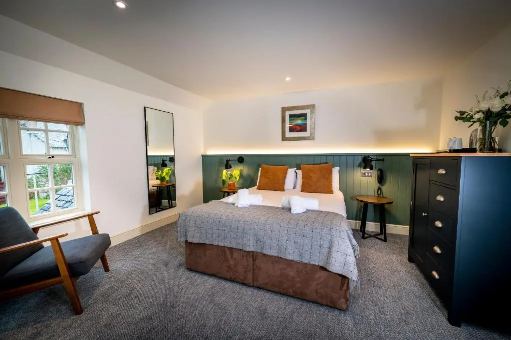 a bedroom with a bed and a chair and a dresser at Loch Ness Inn in Drumnadrochit