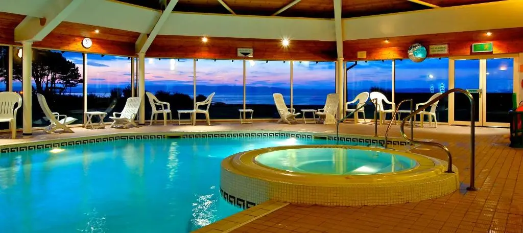 a large swimming pool with chairs and tables in a building at Sea View Lodge in Nairn