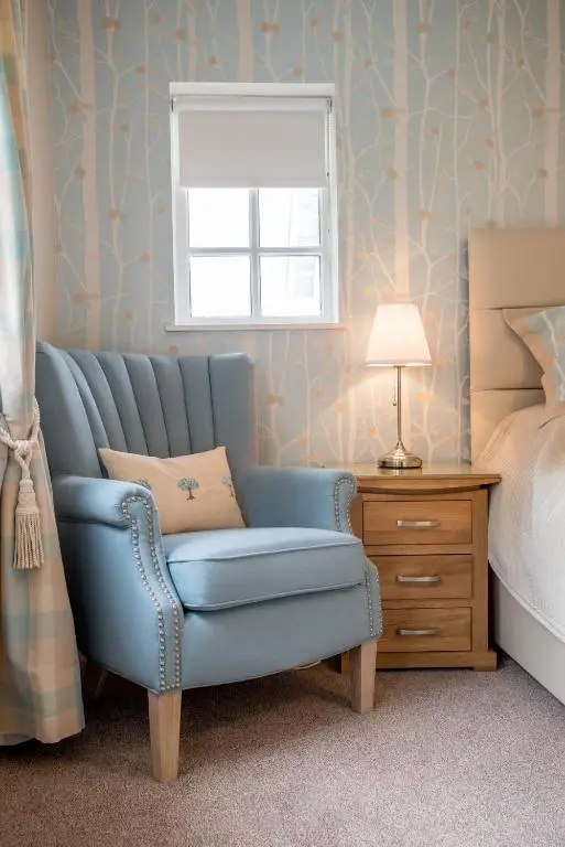 a bedroom with a blue chair and a bed at Sea View Lodge in Nairn