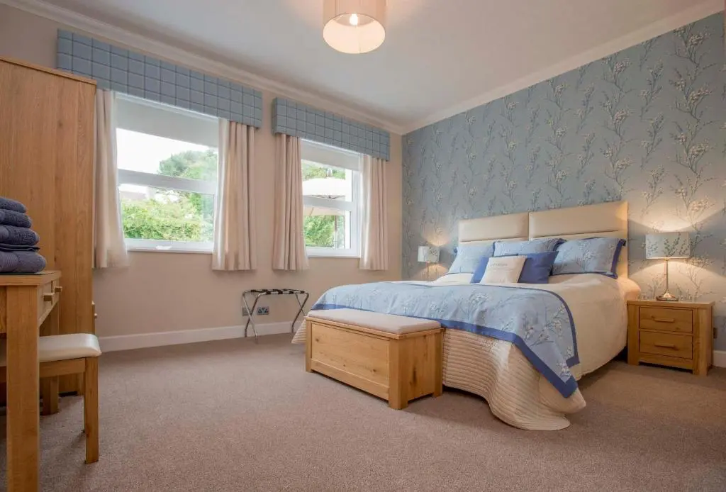 a bedroom with a bed with blue walls and windows at Sea View Lodge in Nairn