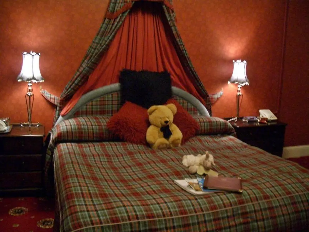 a teddy bear sitting on a bed with two stuffed animals at Atholl Arms in Blair Atholl