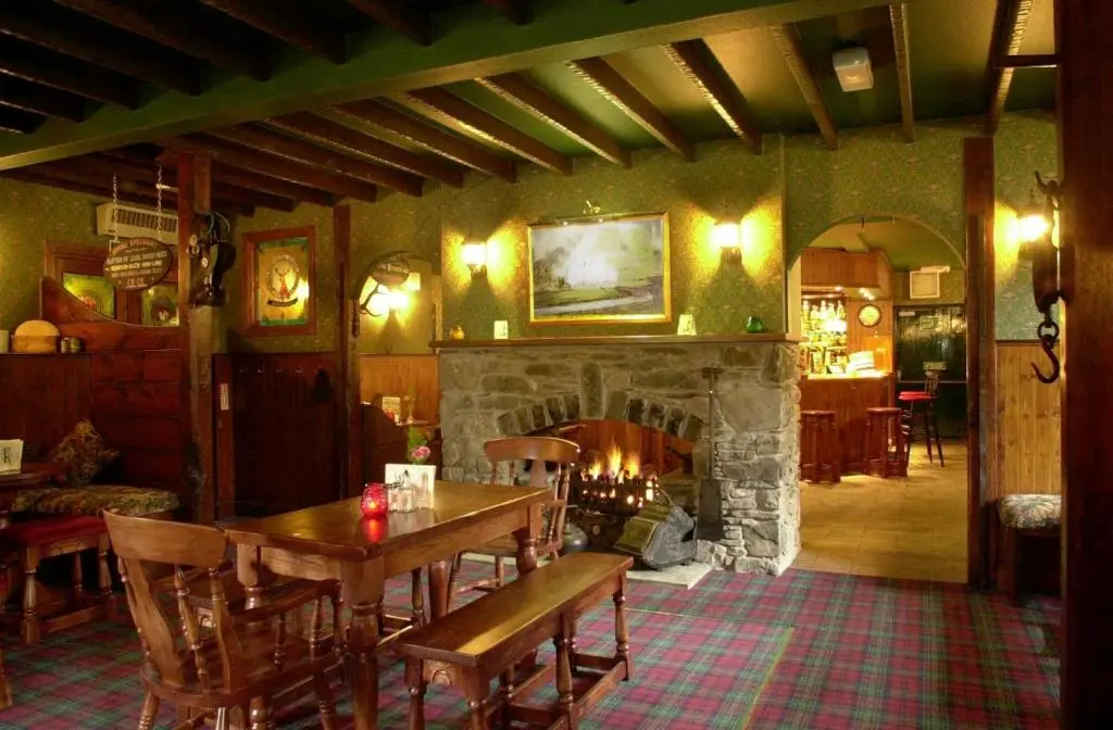 a dining room with a table and a fireplace at Atholl Arms in Blair Atholl