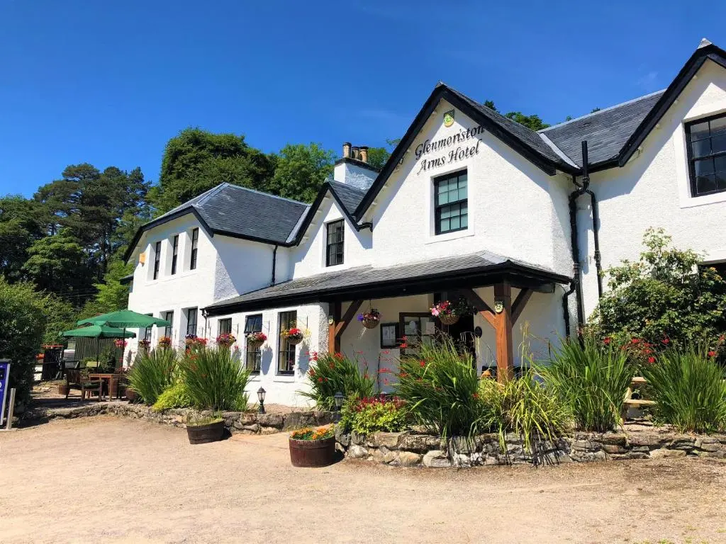 a white building with plants in front of it at Glenmoriston Arms Hotel in Invermoriston