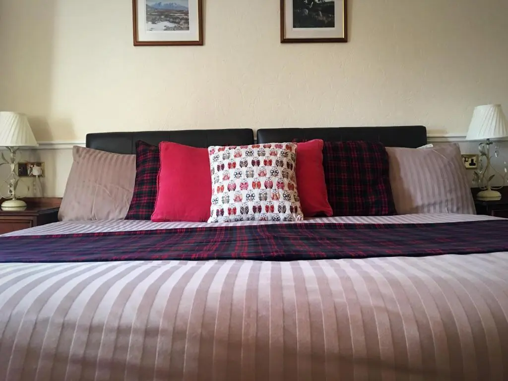 a bed with several pillows on top of it at Glenmoriston Arms Hotel in Invermoriston