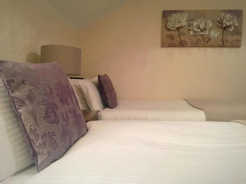 a bedroom with two beds and a painting on the wall at Glenmoriston Arms Hotel in Invermoriston