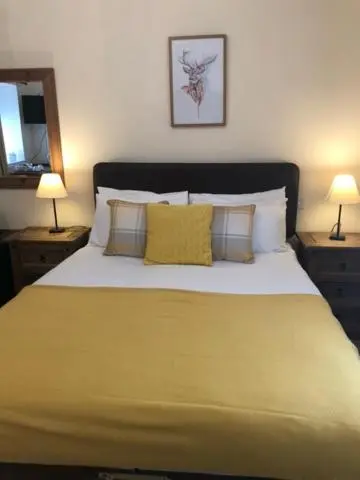 a bedroom with a large yellow bed with two lamps at Glenmoriston Arms Hotel in Invermoriston