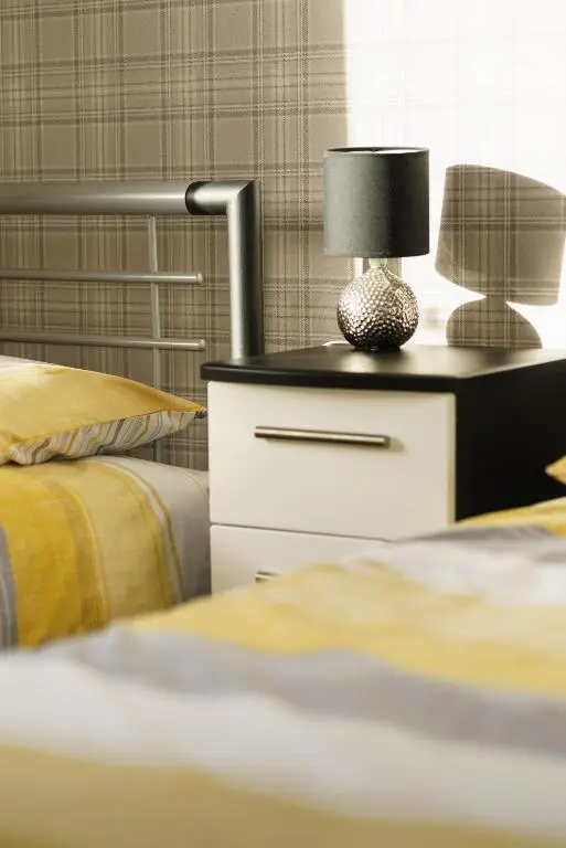a nightstand with a lamp on it next to two beds at Lossiemouth Haven in Lossiemouth