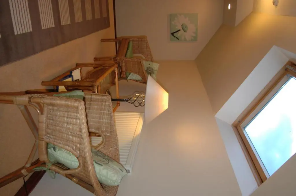 an attic room with wicker chairs and a window at Dunhallin House in Inverness