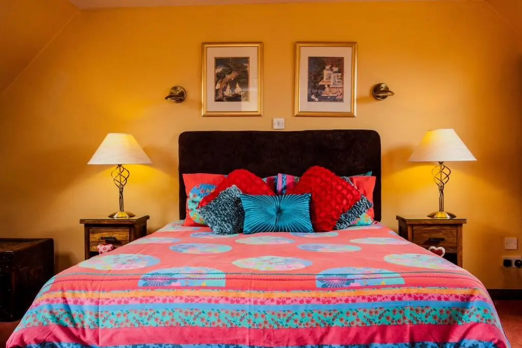 a bedroom with a bed with a colorful bedspread and two lamps at Dunhallin House in Inverness