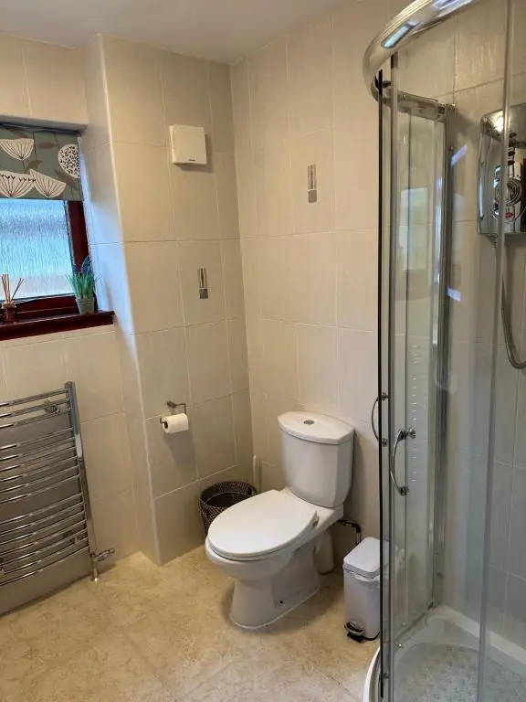 a bathroom with a toilet and a glass shower at Dunhallin House in Inverness