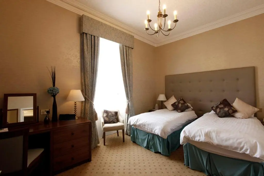 a hotel room with two beds and a window at Mackays Hotel in Wick