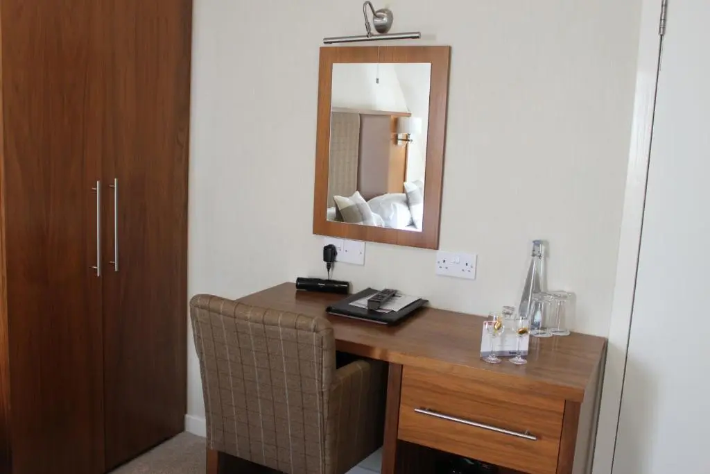 a room with a desk with a mirror and a chair at Mackays Hotel in Wick