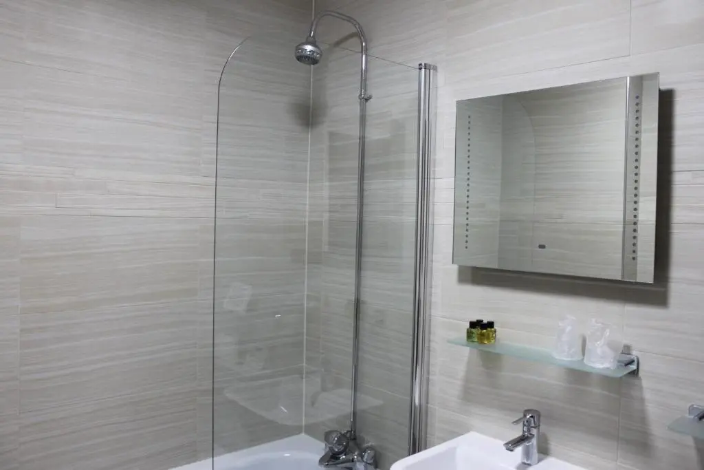 a bathroom with a shower and a sink and a mirror at Mackays Hotel in Wick