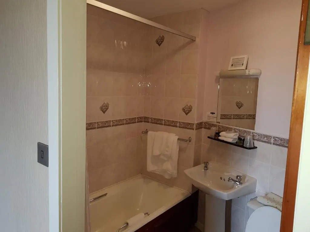 a bathroom with a bath tub and a sink at Mackays Hotel in Wick