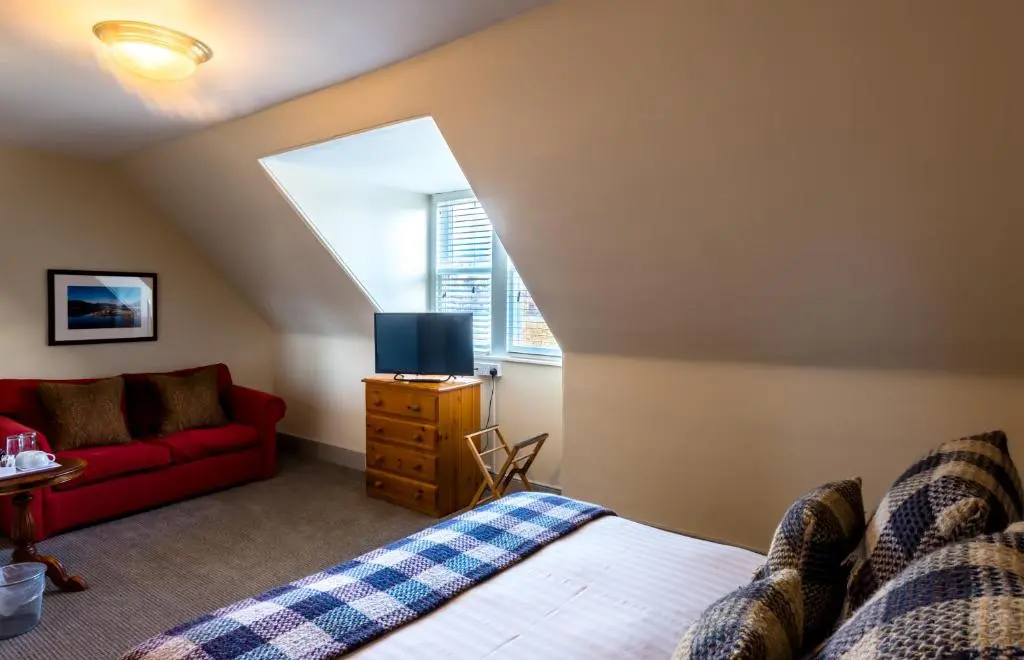a bedroom with a bed and a red couch at Inch Hotel in Fort Augustus