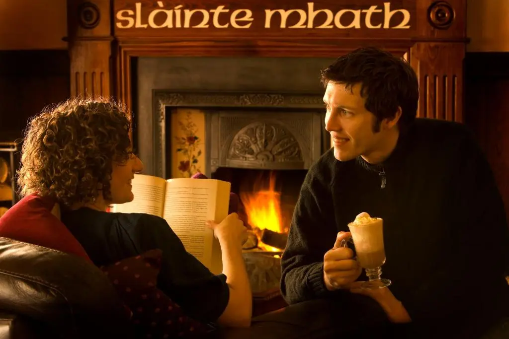 a man and a woman sitting in front of a fireplace at Inch Hotel in Fort Augustus