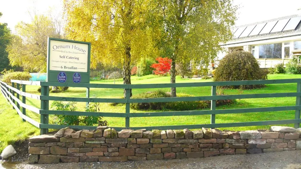 a fence with a sign in front of a building at Ornum Cottage in Beauly