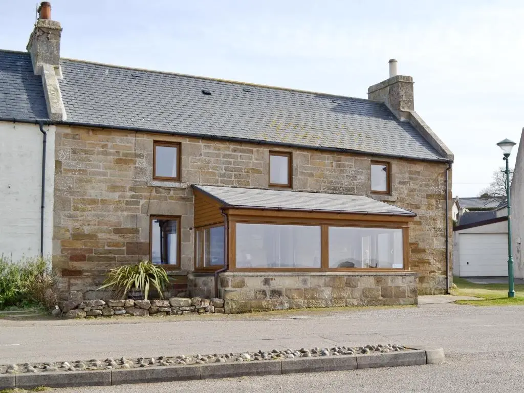 a brick house with a large window at Sandy's Hoose in Portmahomack