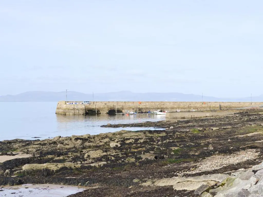 a pier in the water next to a beach at Sandy's Hoose in Portmahomack