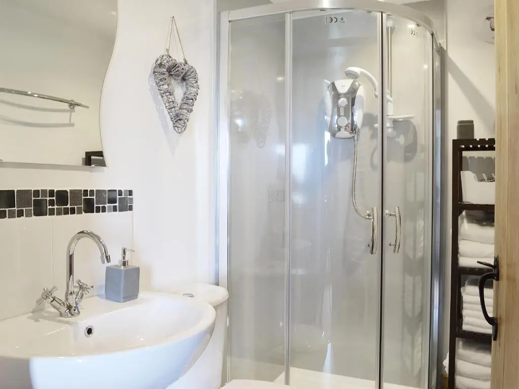 a bathroom with a glass shower and a sink at Sandy's Hoose in Portmahomack