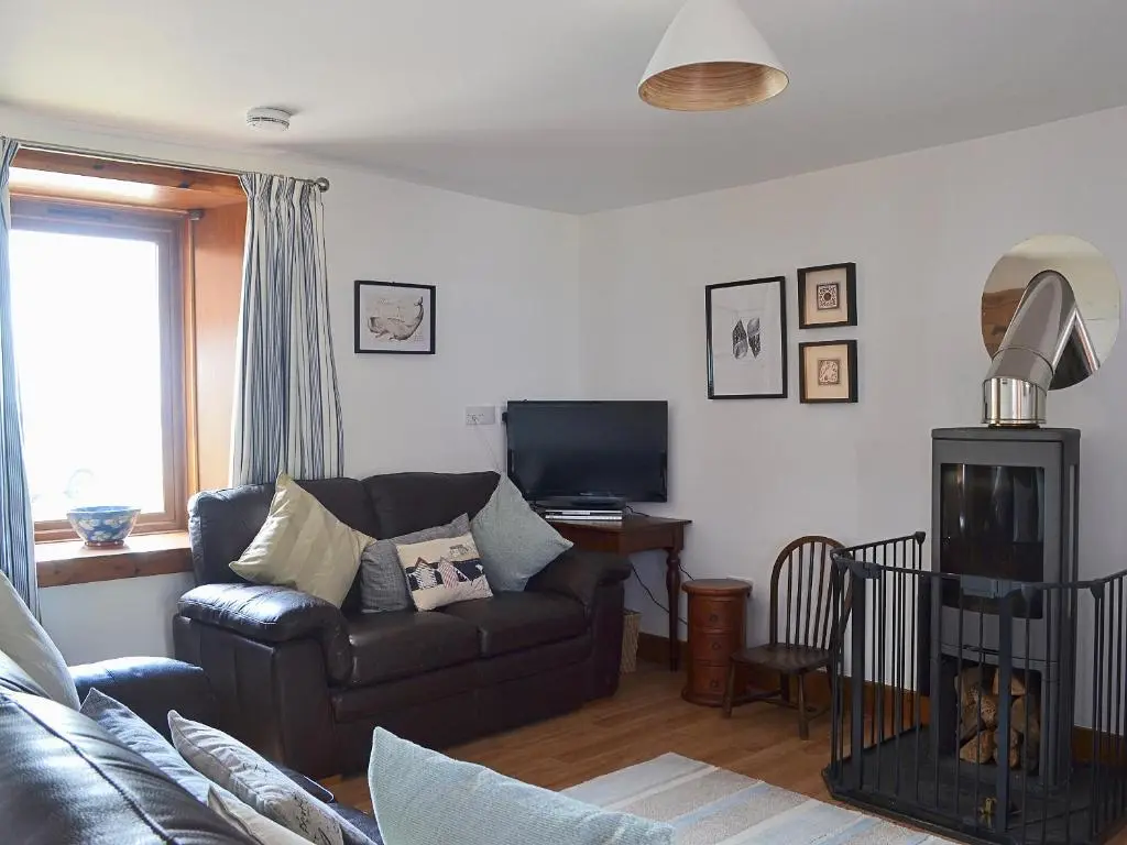a living room with a couch and a television at Sandy's Hoose in Portmahomack
