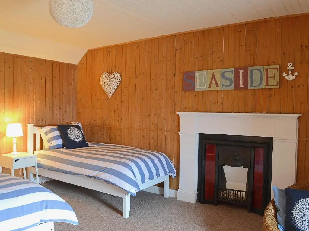 a bedroom with a bed and a fire place at Sandy's Hoose in Portmahomack