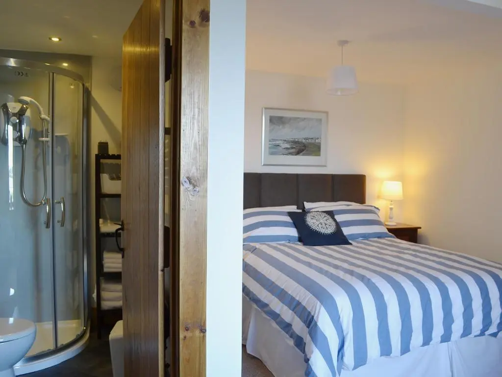 a bedroom with a bed and a bathroom with a shower at Sandy's Hoose in Portmahomack