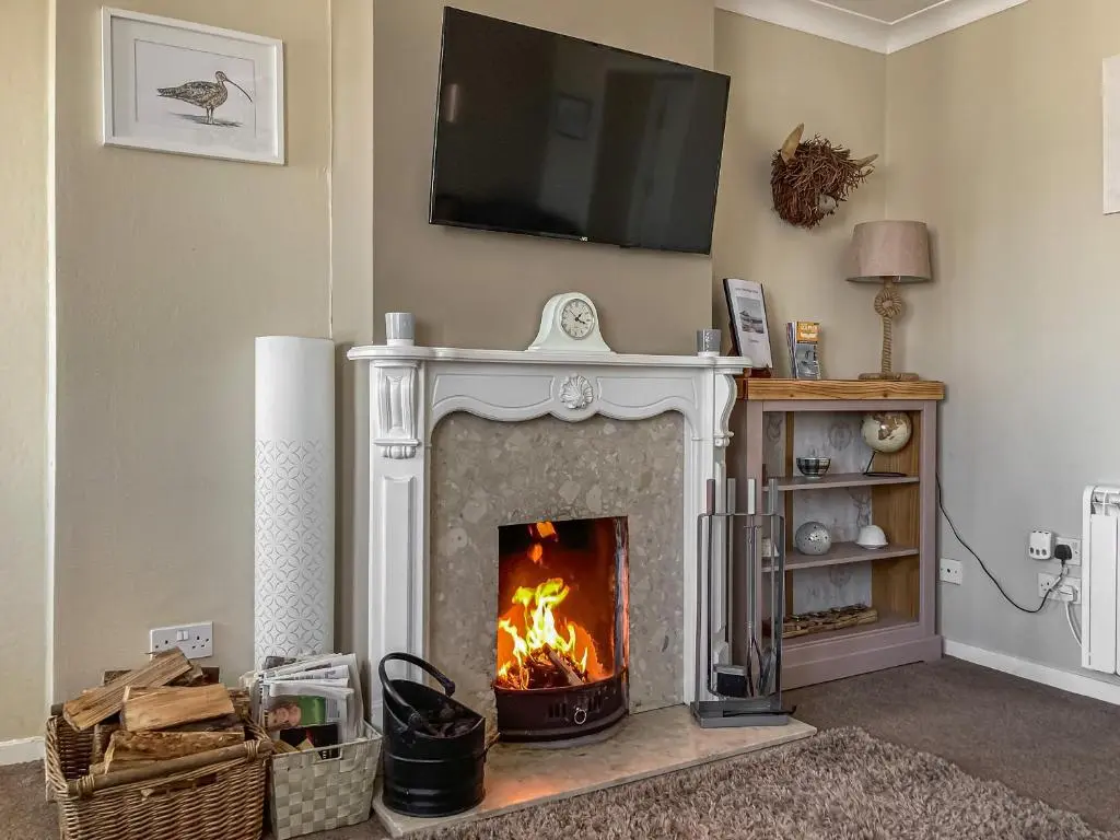 a living room with a fireplace with a tv above it at Cross Tides in Hilton of Cadboll